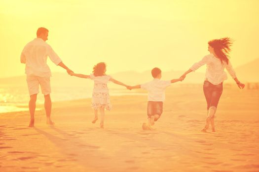 happy young family have fun on beach run and jump  at sunset