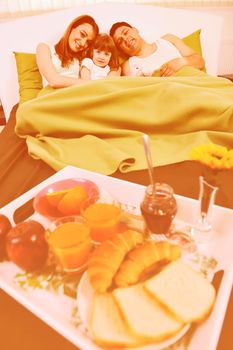 happy young family eat breakfast in bed at morning 