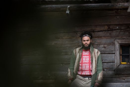 portrait of young hipster,  man with beard in front of old vintage wooden house