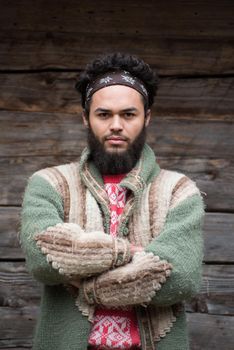 portrait of young hipster,  man with beard in front of old vintage wooden house