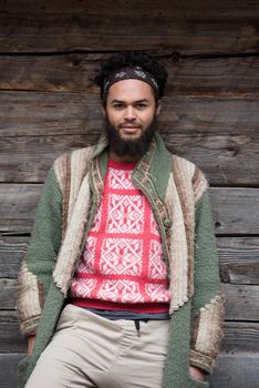 portrait of young hipster,  man with beard in front of old vintage wooden house