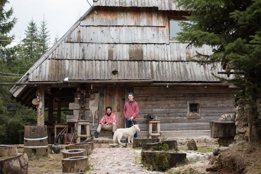 hipsters couple portrait, two young  man with white husky dog  sitting in front of old wooden retro house