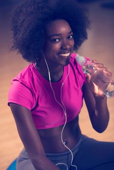 happy african american woman with a curly afro hairstyle in a  gym relaxing after pilates workout