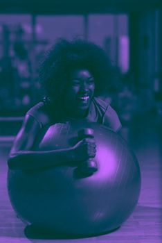 happy african american woman with a curly afro hairstyle in a  gym relaxing after pilates workout duo tone filter