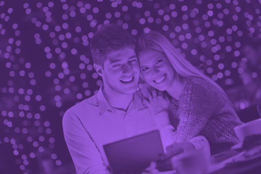 happy young couple with a tablet computer in restaurant