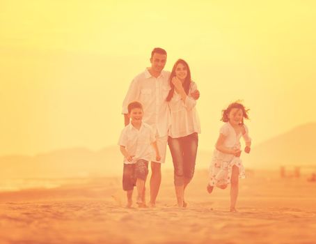 happy young family have fun on beach run and jump  at sunset