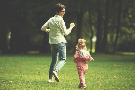 happy family playing together outdoor  in park mother with kids  running on grass