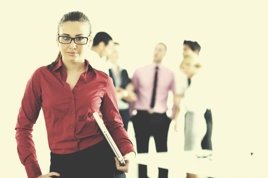 Successful business woman standing with her staff in background at modern bright office