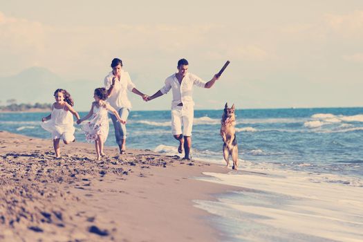 happy young family in white clothing have fun and play with beautiful dog at vacations on beautiful beach