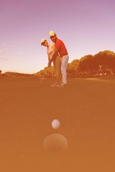 male golf instructor teaching female golf player, personal trainer giving lesson on golf course