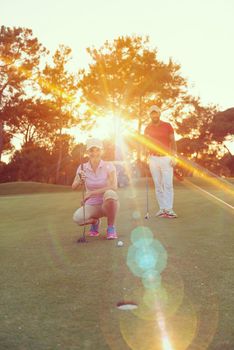portrait of happy young  couple on golf course with beautiful sunset in background