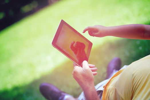 grandfather and child in park using tablet computer