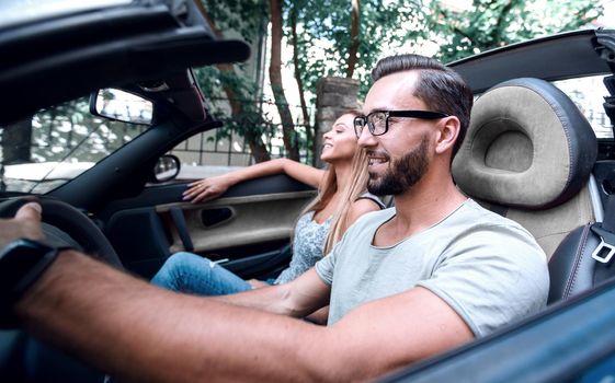 young man sitting behind the wheel of a luxury car. the concept of a successful life