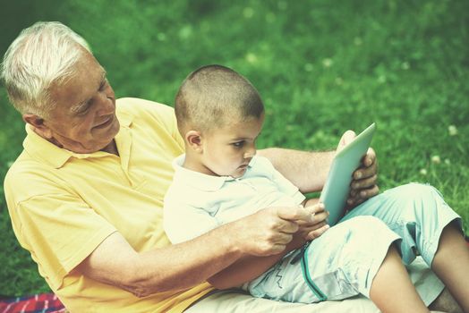 grandfather and child using tablet computer in park