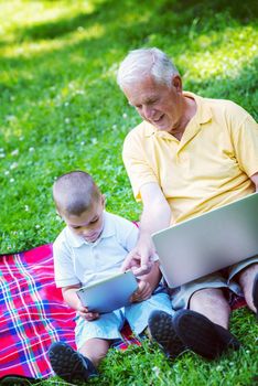 grandfather and child using tablet computer in park