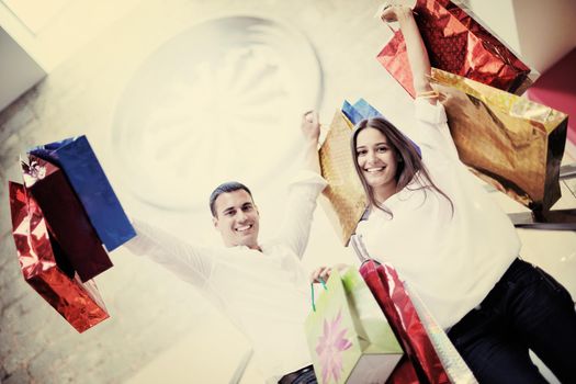 happy young couple with bags in shopping centre mall