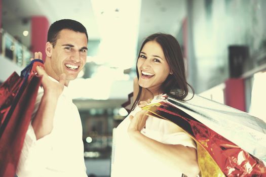 happy young couple with bags in shopping centre mall