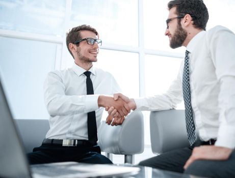 business people shake hands sitting in the hall of the business center. the concept of cooperation