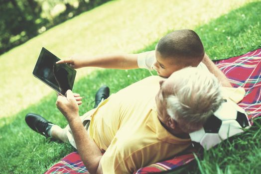 grandfather and child using tablet computer in park