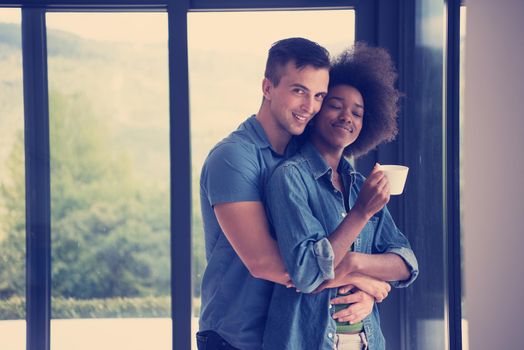 romantic happy young multiethnic couple enjoying morning coffee by the window in their luxury home