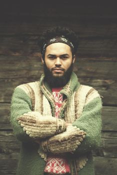 portrait of young hipster,  man with beard in front of old vintage wooden house