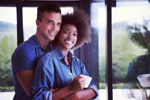 romantic happy young multiethnic couple enjoying morning coffee by the window in their luxury home