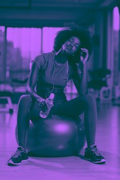 happy african american woman with a curly afro hairstyle in a  gym relaxing after pilates workout duo tone filter