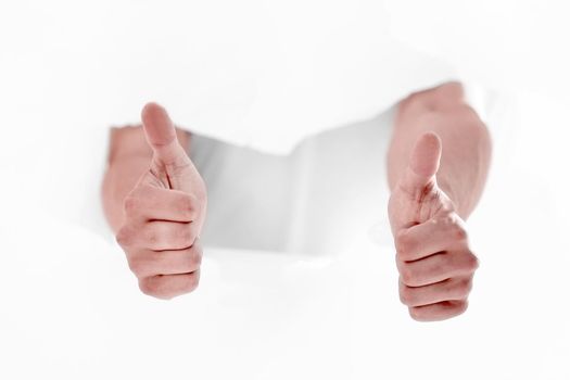 man breaking through the paper wall and showing thumbs up.photo with copy space