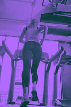 sport, fitness, lifestyle, technology and people concept - smiling woman exercising on treadmill in gym duo tone