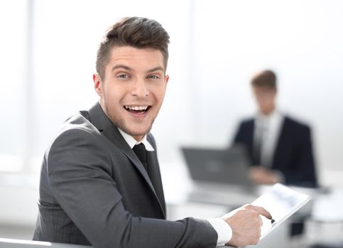 happy businessman smiling while sitting in office and using tablet