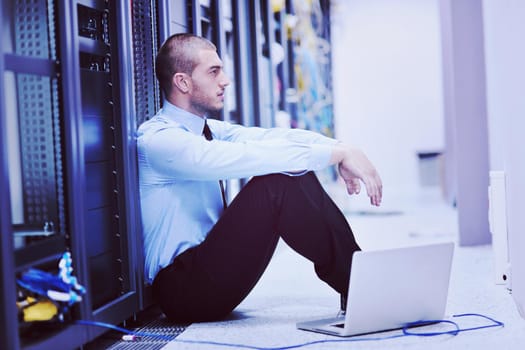 young engeneer business man with thin modern aluminium laptop in network server room