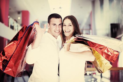 happy young couple with bags in shopping centre mall