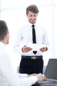 young businessmen communicate in the office. one looks at the tablet. The second one offers ideas on business