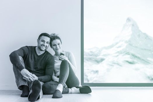 happy young couple sitting near window at home on cold winter day