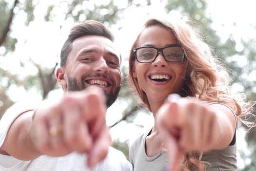 close up.happy newlyweds standing in the Park and pointing at you.photo with copy space