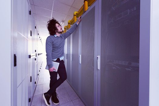 Male IT engineer working on a tablet computer in server room at modern data center