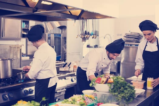 Professional team cooks and chefs preparing meals at busy hotel or restaurant  kitchen