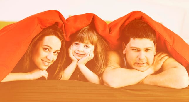 happy young family relaxing in bed 