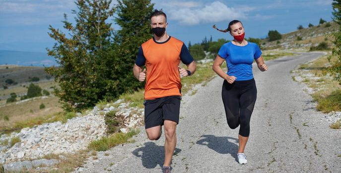 Couple running in nature at morning wearing protective face masks