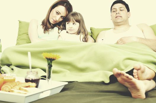 happy young family eat breakfast in bed at morning 