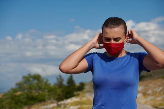 sporty woman with protective face mask having a break and relaxing after running