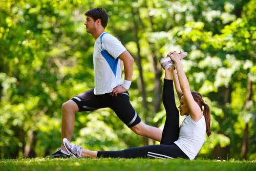 young health couple doing stretching exercise relaxing and warm up after jogging and running in park