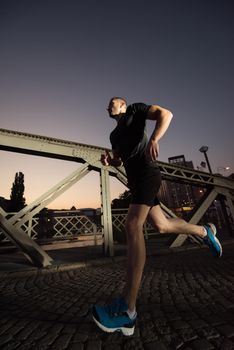 urban sports, young healthy man jogging across the bridge in the city at early morning in night