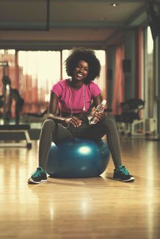 happy african american woman with a curly afro hairstyle in a  gym relaxing after pilates workout