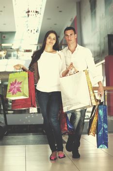 happy young couple with bags in shopping centre mall