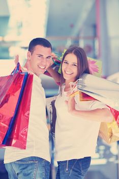 happy young couple with bags in shopping centre mall