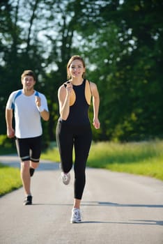 Young couple jogging in park at morning. Health and fitness concept