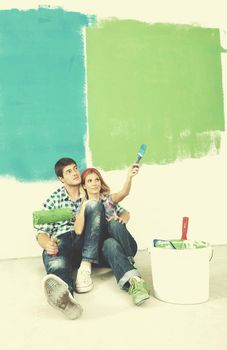 happy young couple paint in green and blue color white wall of their new home