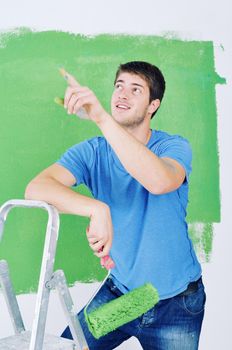 handsome young man paint in blue and green color  white wall of new home