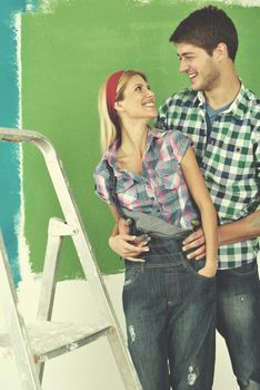 happy young couple paint in green and blue color white wall of their new home